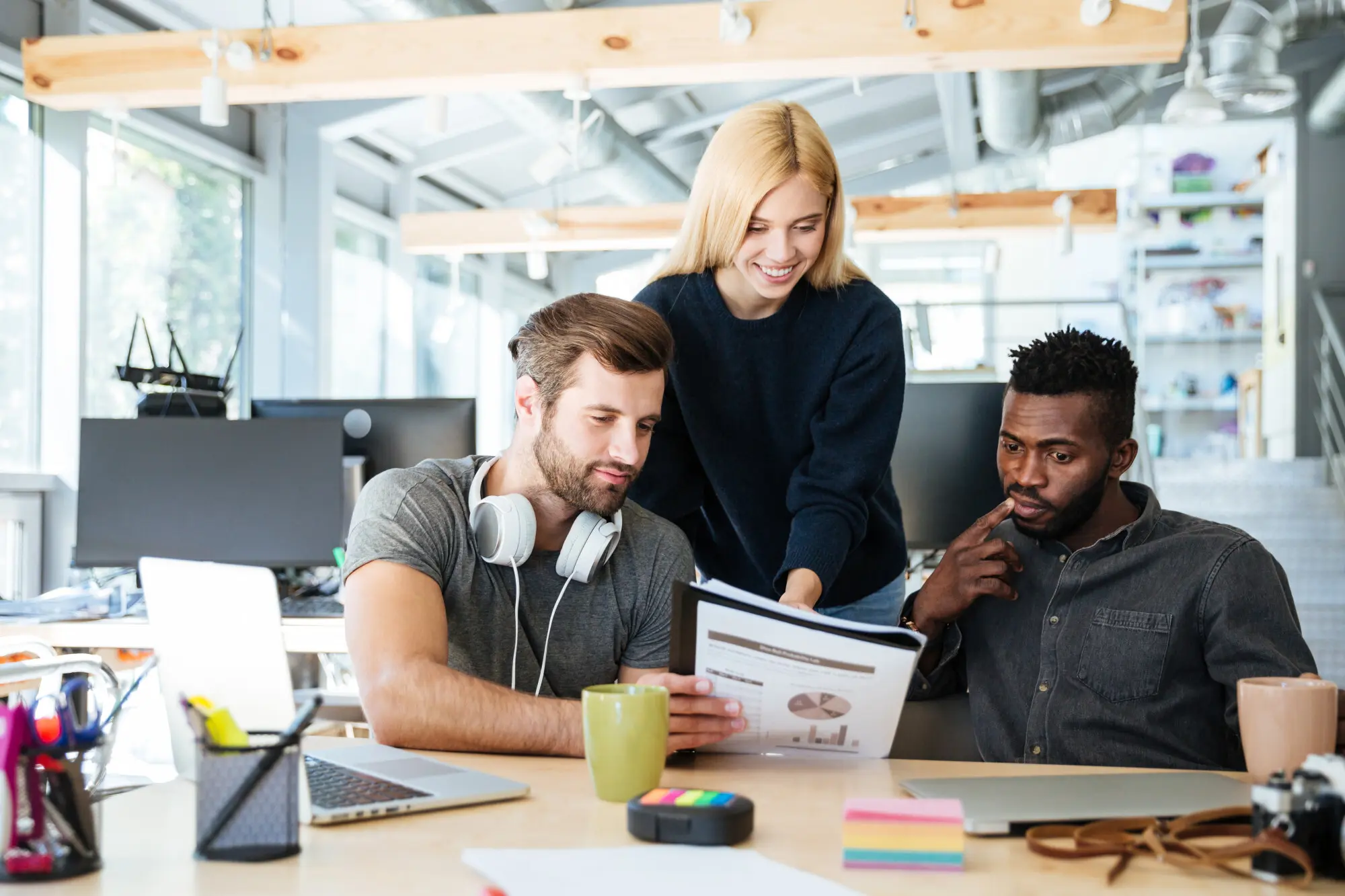 Junge, glückliche Kolleginnen und Kollegen sitzen in einem Coworking-Büro.